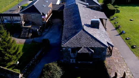 Drone-Aéreo-Hacia-Atrás-Disparado-Sobre-Una-Antigua-Casa-Hecha-De-Paredes-De-Piedra-Convertida-En-Casa-De-Turismo-Rural-En-Manon,-Lugo,-Galicia,-España