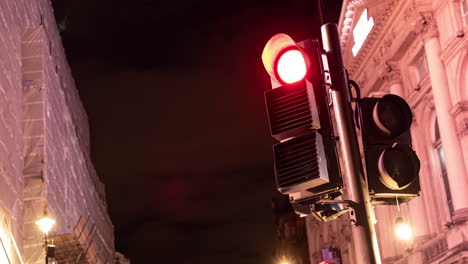 Timelapse-of-a-busy-London-intersection's-traffic-lights-working,-lights-flash-and-illuminate-the-buildings-on-a-busy-London-Street