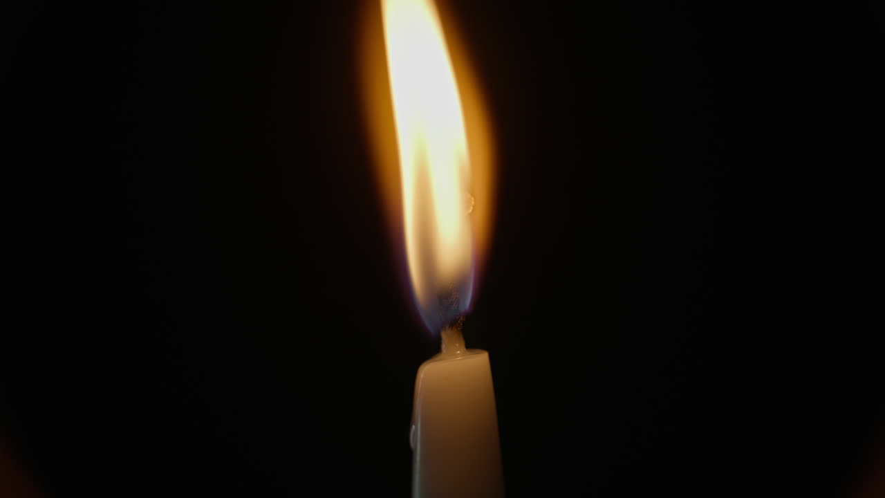 Flamme d’une bougie soufflée par le vent sur fond noir isolé. Un chandelier de cire.