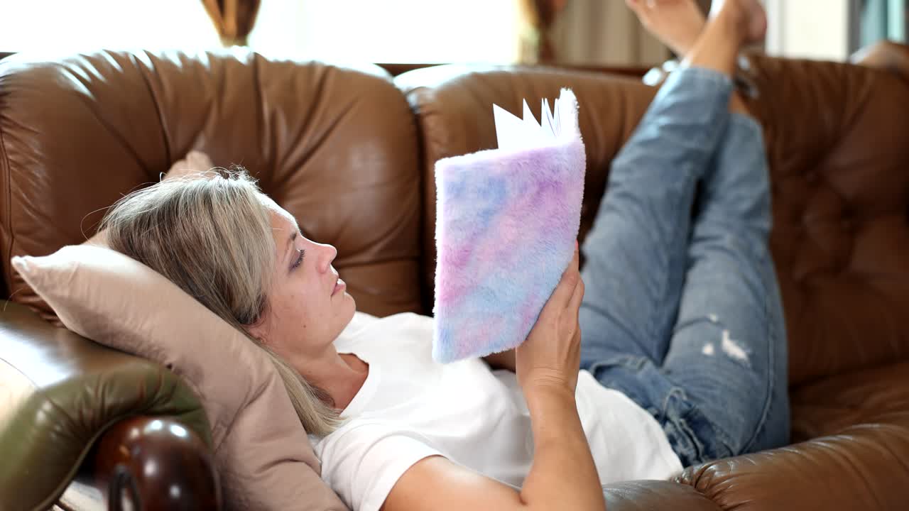 Kvinde, der læser en bog på en sofa