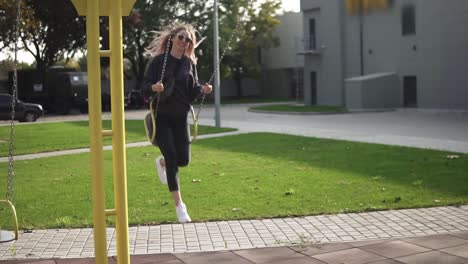 young woman swinging on a swing on the backyard, happily smiling