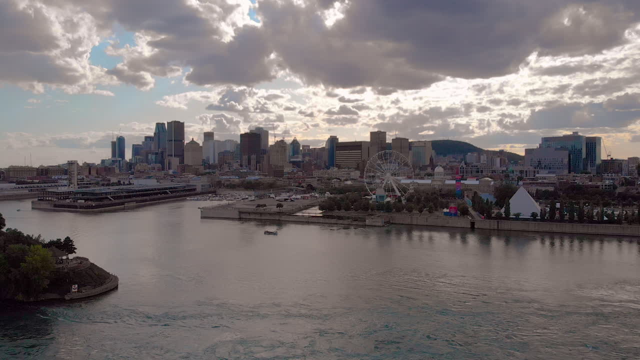 An aerial shot of Downtown Montreal from over St Lawrence River. The camera tilts upward from the river and reveals the city during sundown.