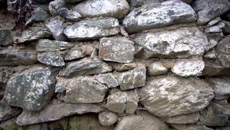 an ancient stone wall of a ruined house amongst the grass. old house, ruins, background