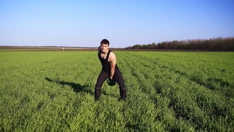 Front-view-of-muscular-young-man-engaged-in-lifting-in-the-open-area.-Raises-the-weight-with-the-left-hand.-The-sun-is-shining