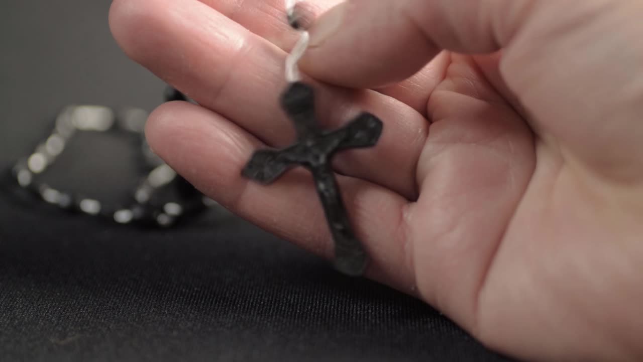 mano sujetando un rosario con crucifijo de cerca