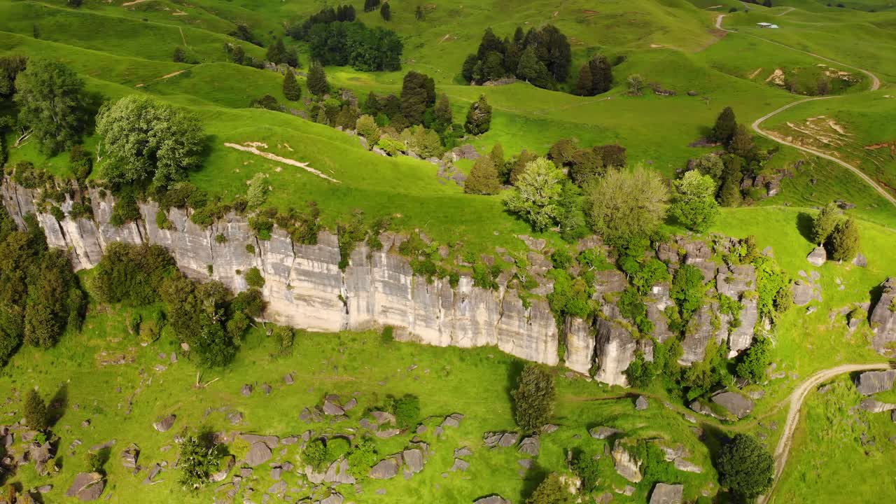 Bird's Eye View Of Rock Wall Formation With Curve Trails Between Countryside Field At Daytime In North Island, New Zealand