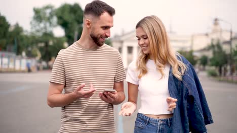 Zwei-Junge-Freunde-Schauen-Auf-Das-Telefon-Und-Gehen-Die-Straße-Entlang