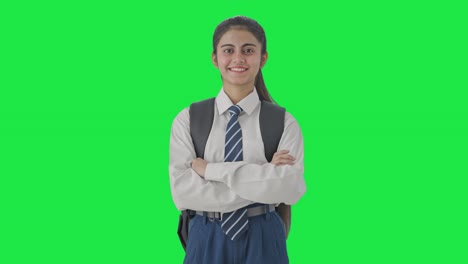 niña de escuela india feliz de pie con las manos cruzadas con confianza pantalla verde