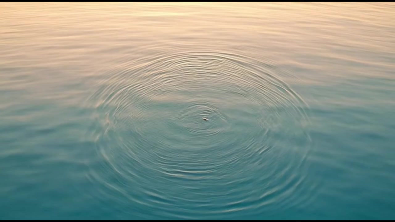 Increspature concentriche che si espandono sulla superficie calma dell'acqua al tramonto