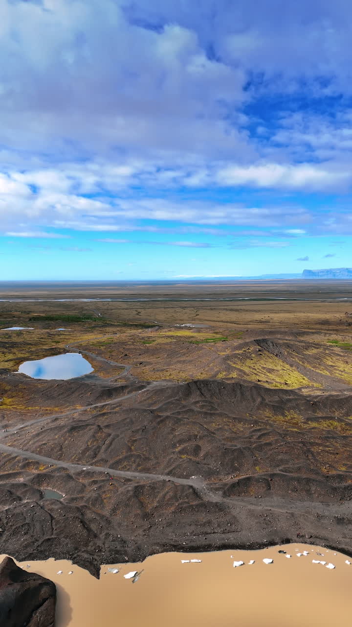 Lakes with ice pieces floating on the surface. Surrealistic rocky landscape of Iceland from top perspective. Vertical video.