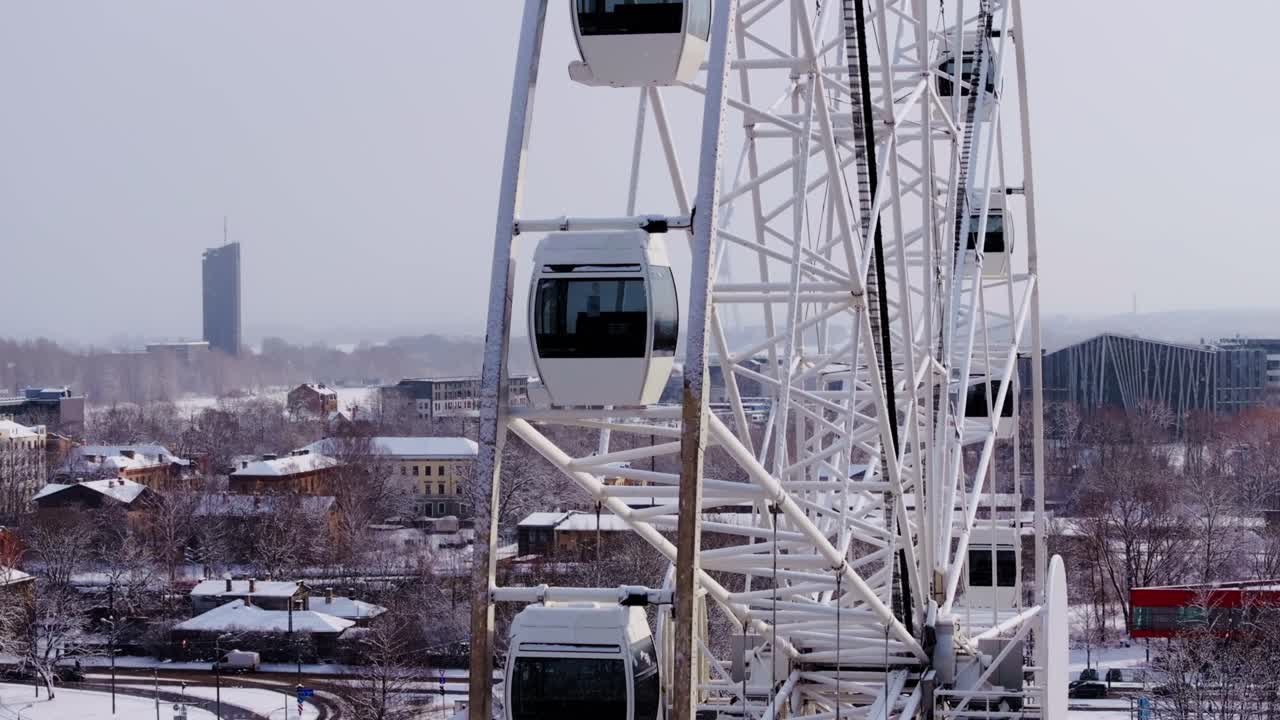 Snow blankets Riga as a Ferris wheel slowly moves above the frosty rooftops, 4K