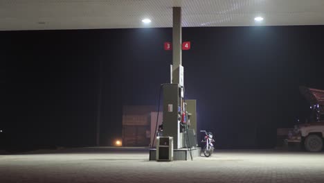 Shot-of-refuelling-station-beside-a-highway-with-bike-parked-at-night-time-in-Punjab,-Pakistan