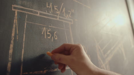 hand of carpenter drafting furniture on chalkboard