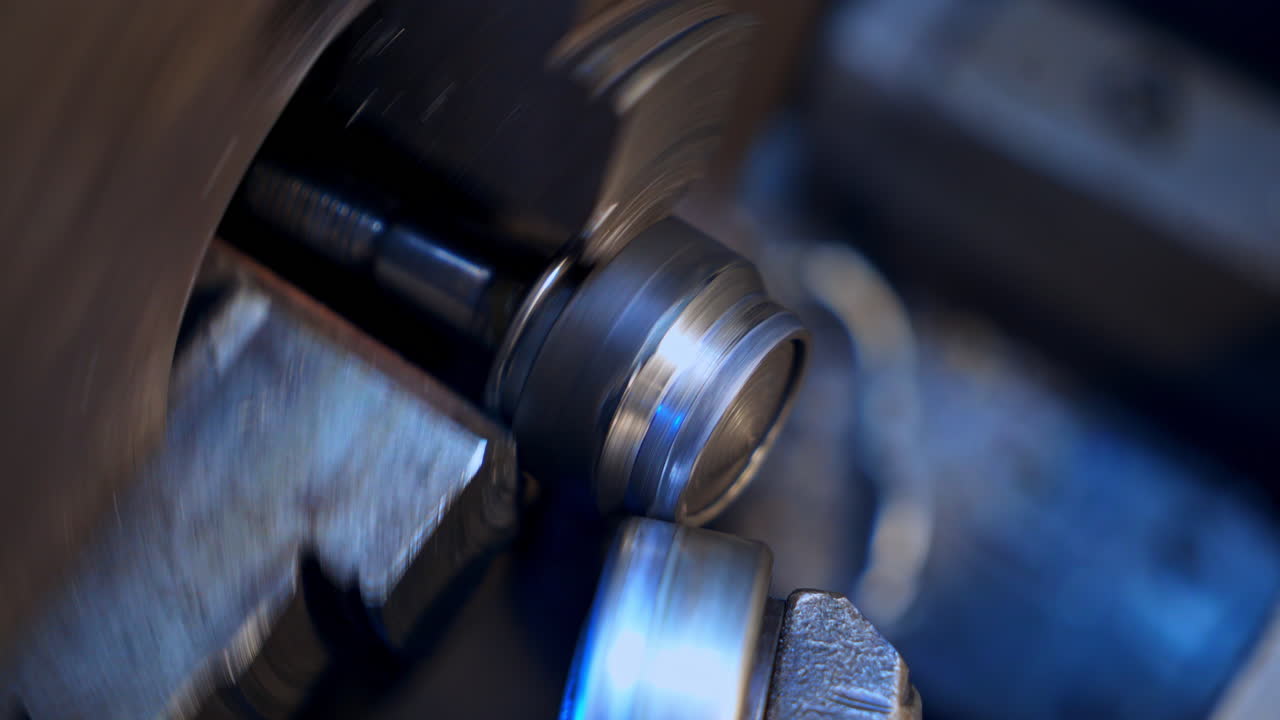 Two attached machine pieces turning to make screw-thread on the detail. Rotating mechanism on the turner's equipment. Close up.