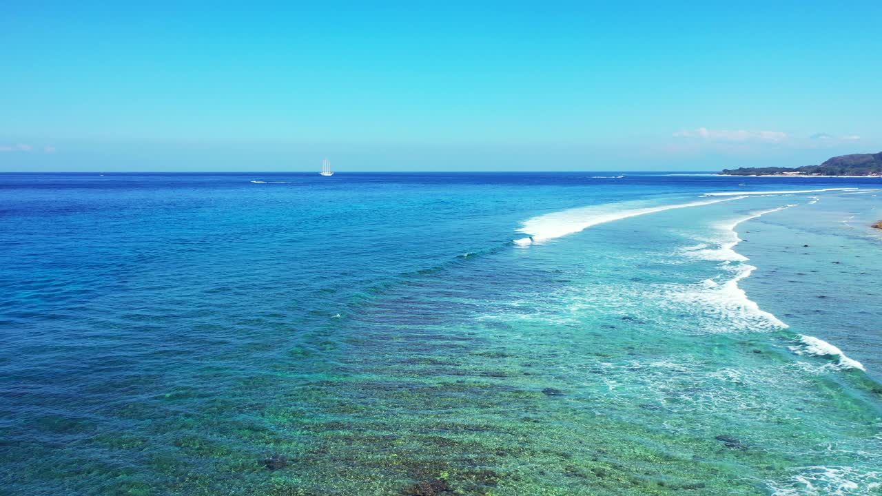 White waves foaming over rocky seabed and corals blending with calm clear water of turquoise lagoon near shore of tropical island in Malaysia