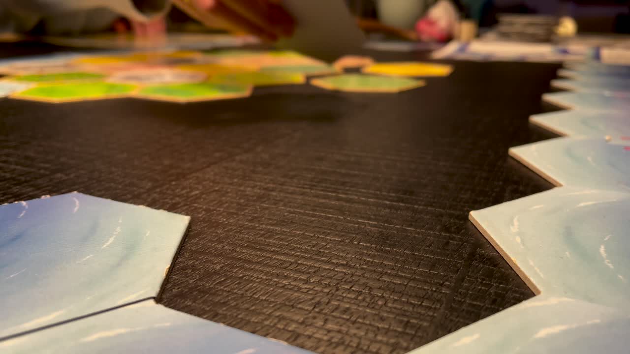 manos colocando fichas hexagonales sobre la mesa