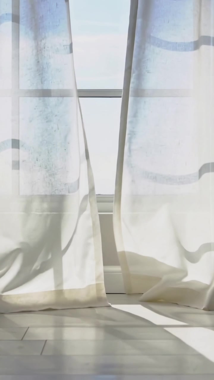 Vertical video: Gentle breeze moving sheer curtains in room window, shifting light on pale floor