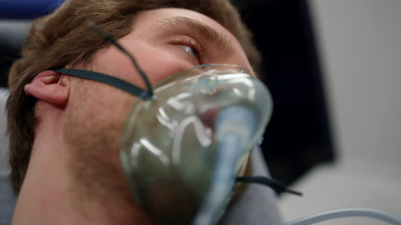 hombre herido con máscara de oxígeno acostado en camillas en el coche de ambulancia