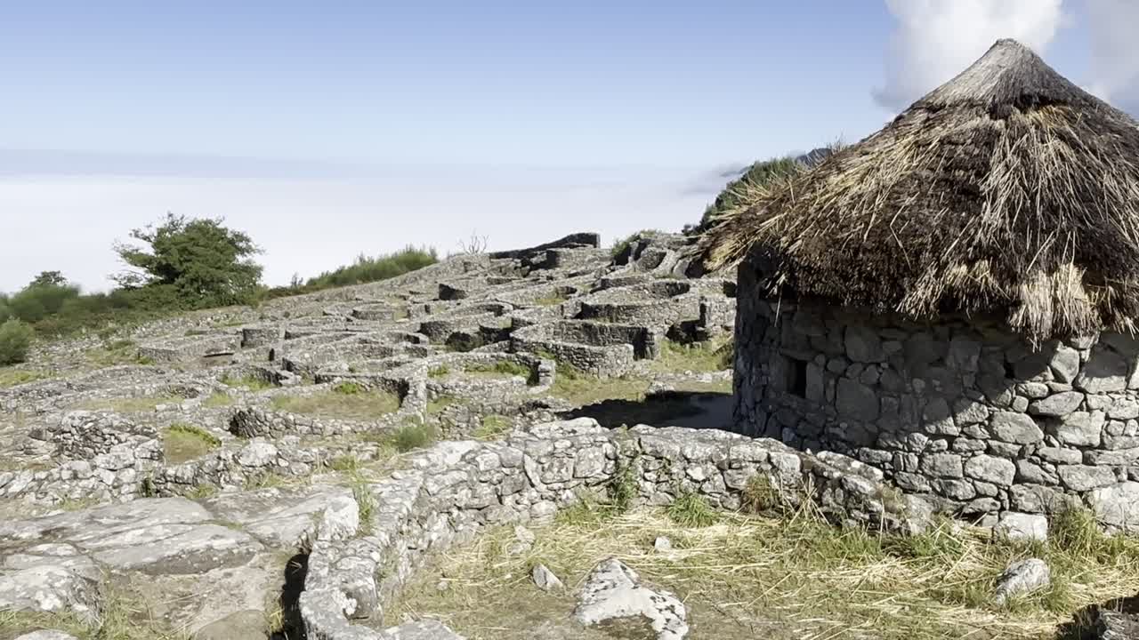 vista de cerca de las antiguas ruinas celtas en santa tecla, galicia, con una montaña cubierta de niebla en el fondo