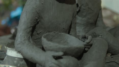 close-up of clay sculpture featuring detailed human figures holding a bowl