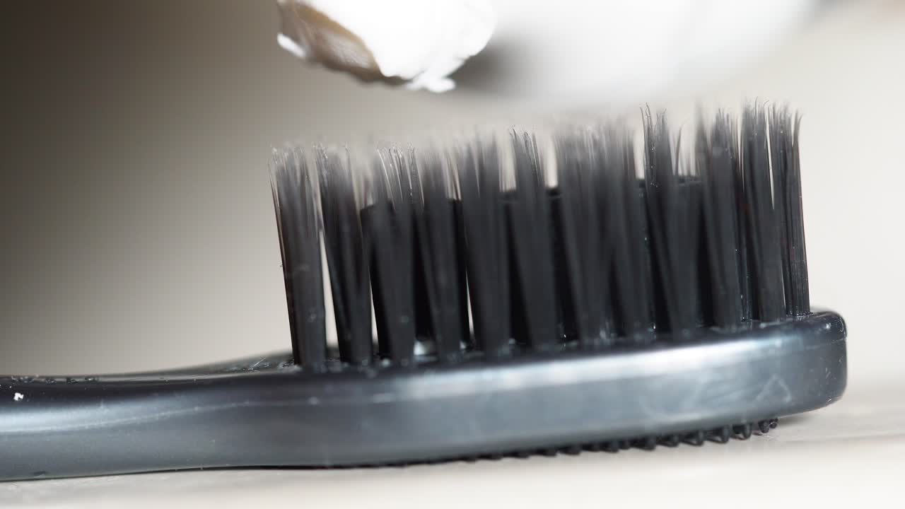 la aplicación de pasta de dientes a un cepillo de dientes negro