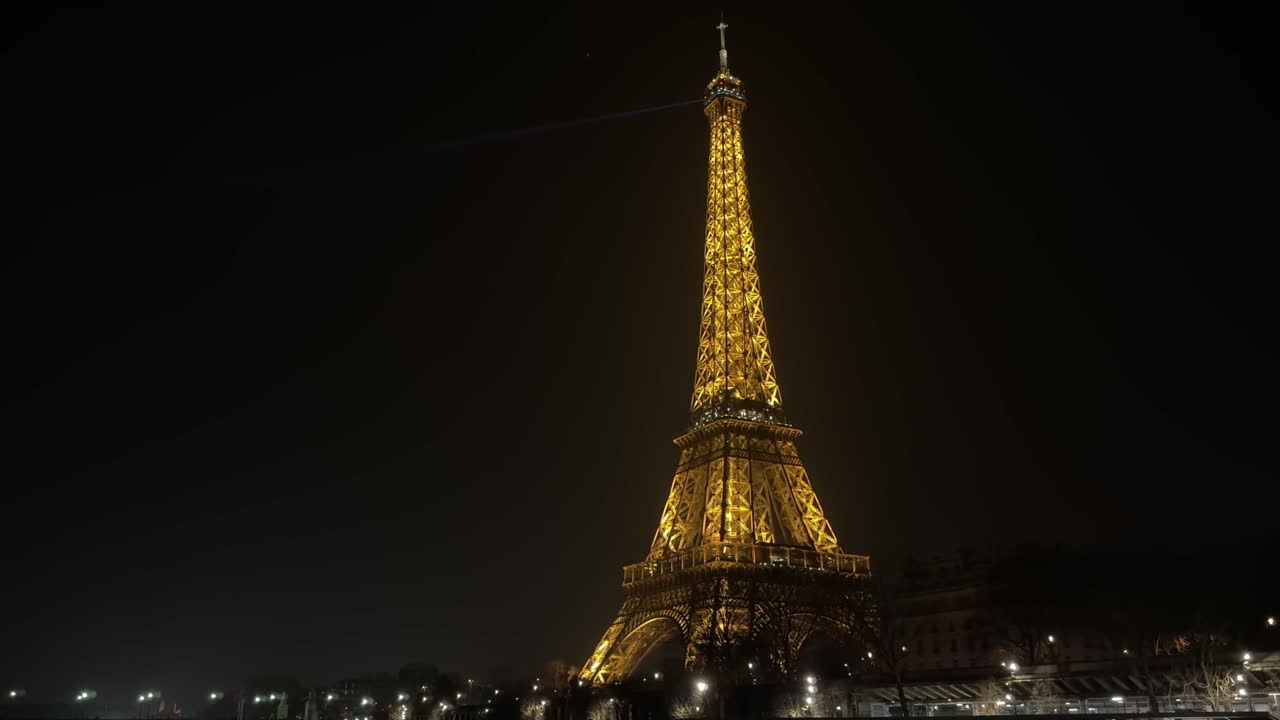 Eiffel Tower glowing with golden lights against a dark night sky in Paris