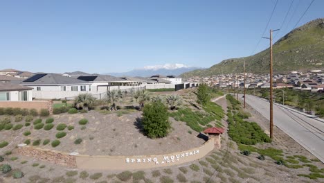 Ascending-drone-view-of-Spring-Mountain-Ranch,-Riverside,-CA,-revealing-snowy-mountains-in-the-back-and-green-mountain-on-the-side-on-a-nice-sunny-day