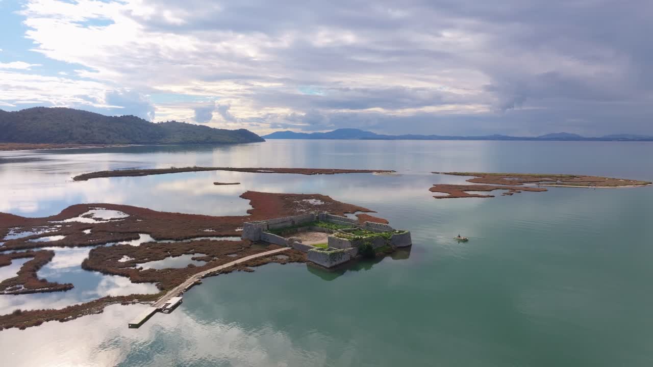 Captura aérea de uma fortaleza histórica rodeada pelo lago, Ksamil
