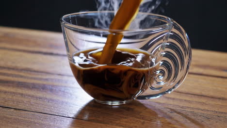 pouring hot coffee into a clear glass cup