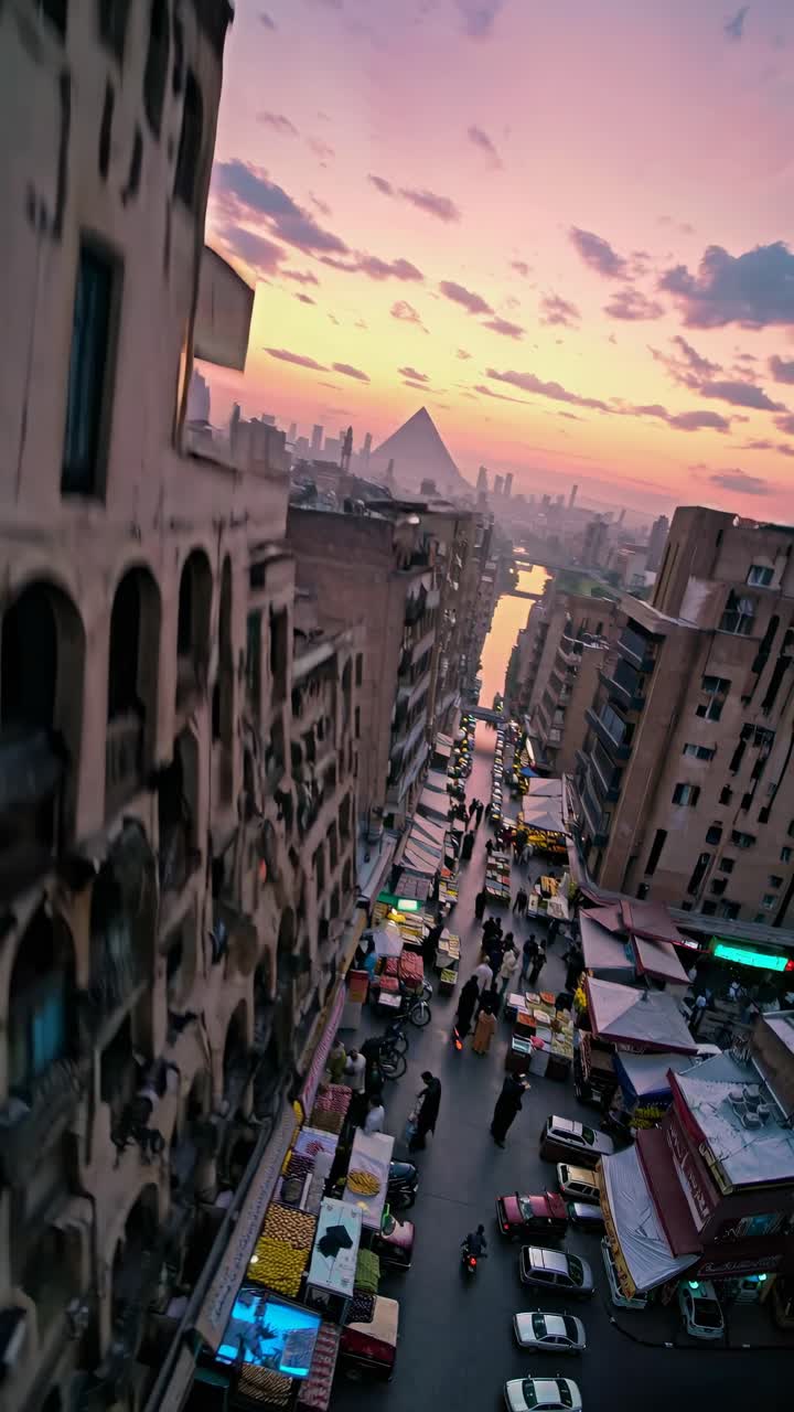 Veduta aerea di una città vivace al tramonto, con una piramide in lontananza.