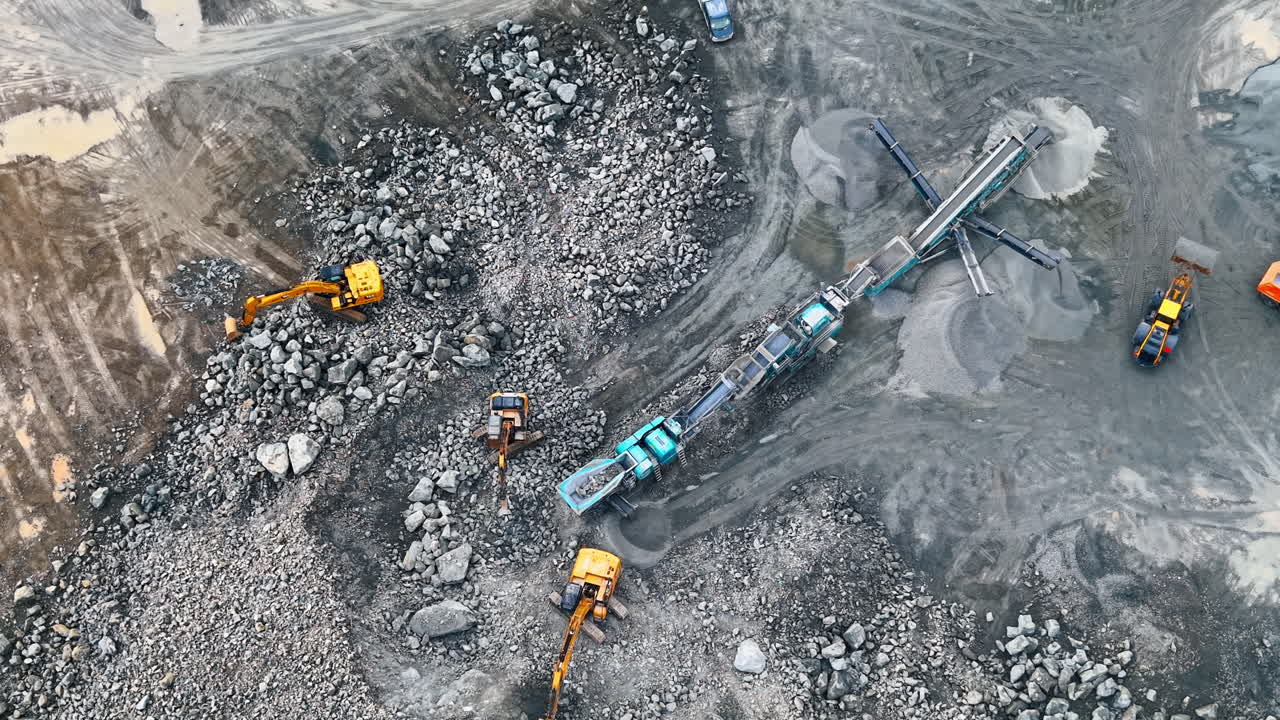 Heavy machinery at site. Workers use heavy machines to move rocks and gravel at a construction site in the early morning