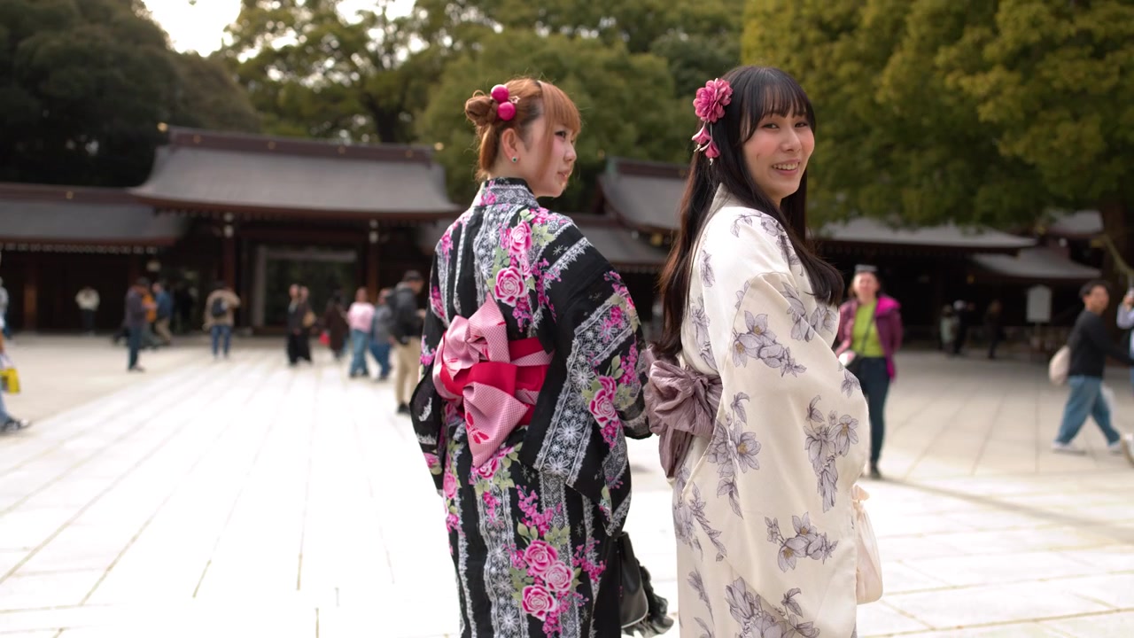 Due donne che indossano kimono tradizionali camminano e si voltano al Santuario Meiji Jingu a Tokyo