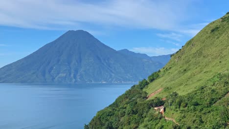 timelapse of central american volcano volcan san pedro in lake atitlan, guatemala on a sunny day with boat traffic over the blue lake water and santa cruz la laguna green hillside in the foreground