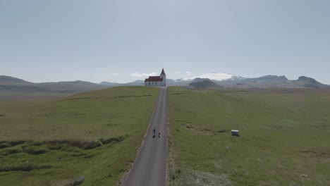 tourist with dog walking along road from church ingjaldshóll, icelandic scenery