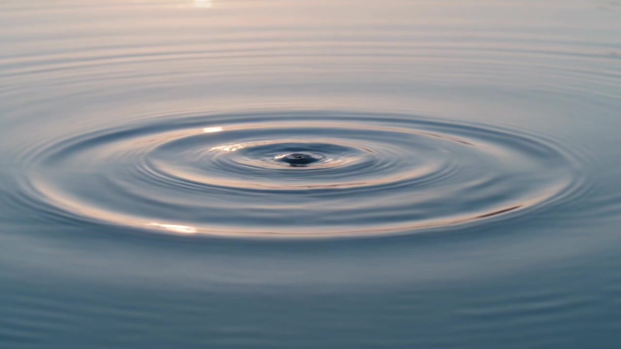 Formando una cresta centrale e increspature d'acqua concentriche che si diffondono su uno stagno calmo, dall'impatto di una goccia.