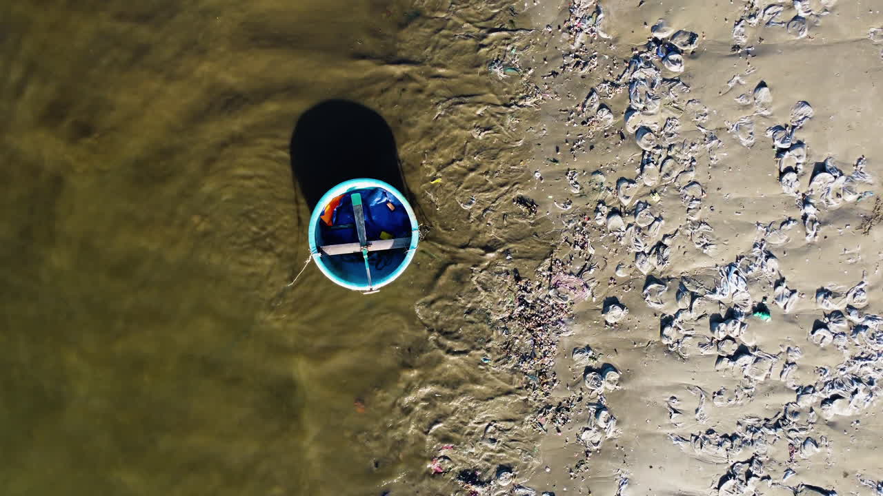 barco de coracle vietnamita tradicional y playa de arena llena de plástico y otra suciedad, vista aérea de arriba hacia abajo