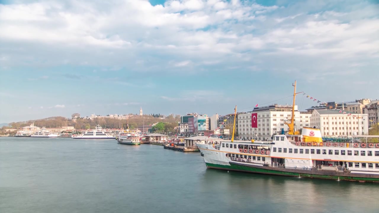 Traffico di navi turistiche e traghetti sul Bosforo vicino alla stazione dei battelli, vista in timelapse dal Ponte di Galata a Istanbul, Turchia. Skyline della città con la collina di Camlica sullo sfondo prima del tramonto in un giorno di primavera.