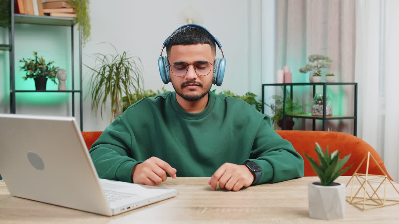 Indian man listening music breathes deeply meditating with concentrated thoughts peaceful at home