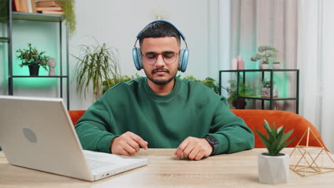 indian man listening music breathes deeply meditating with concentrated thoughts peaceful at home