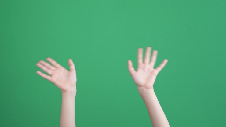 Mani di bambino che salutano, facendo gesti di saluto e di addio su sfondo a schermo verde chroma key.