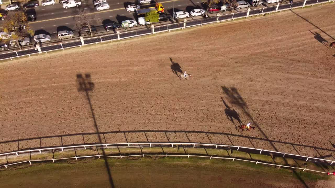 toma aérea de arriba hacia abajo de caballos trotando hasta el punto de partida en el hipódromo de buenos aires durante la puesta de sol