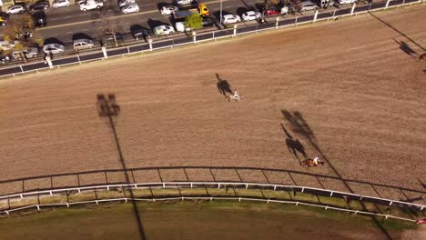 Toma-Aérea-De-Arriba-Hacia-Abajo-De-Caballos-Trotando-Hasta-El-Punto-De-Partida-En-El-Hipódromo-De-Buenos-Aires-Durante-La-Puesta-De-Sol