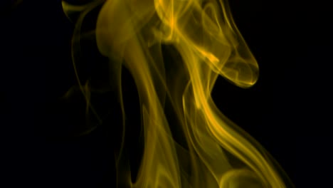 el humo amarillo se eleva lentamente con gracia hacia arriba. el humo de color sopla de abajo hacia arriba. primer plano, aislado sobre un fondo negro