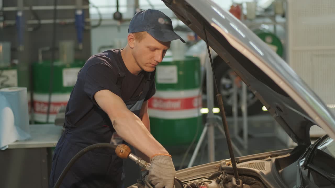 el mecánico de automóviles está cambiando el aceite del motor en un motor en la estación de automóviles. cambio de aceite automatizado con equipos modernos