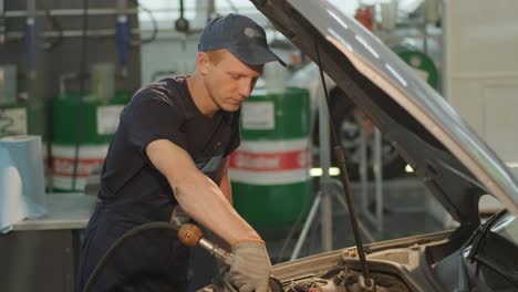 auto mechanic is changing motor oil into a engine at car station. automated oil change with modern equipment