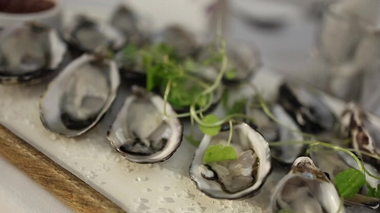 Detailed close-up shot of shucked oysters arranged on coarse salt, topped with fresh microgreens, in soft natural light. Elegant gourmet seafood presentation, perfect for upscale dining visuals.