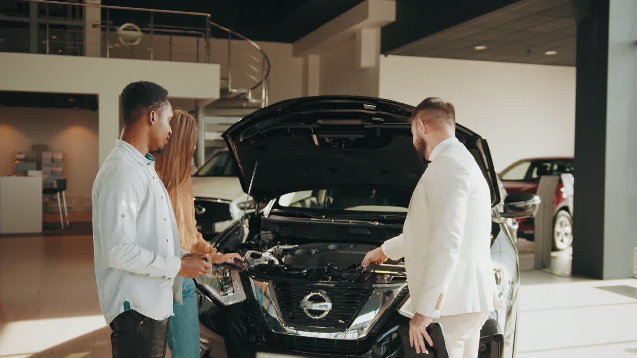 clientes examinando un motor de automóvil en un concesionario
