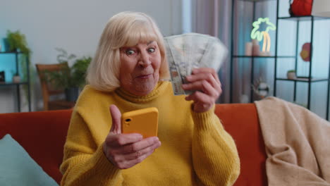 Mujer-Abuela-Feliz-Contando-Dinero-En-Efectivo-Usando-Un-Teléfono-Inteligente,-Ingresos-Ahorra-Lotería-Ganar-Presupuesto-En-Casa