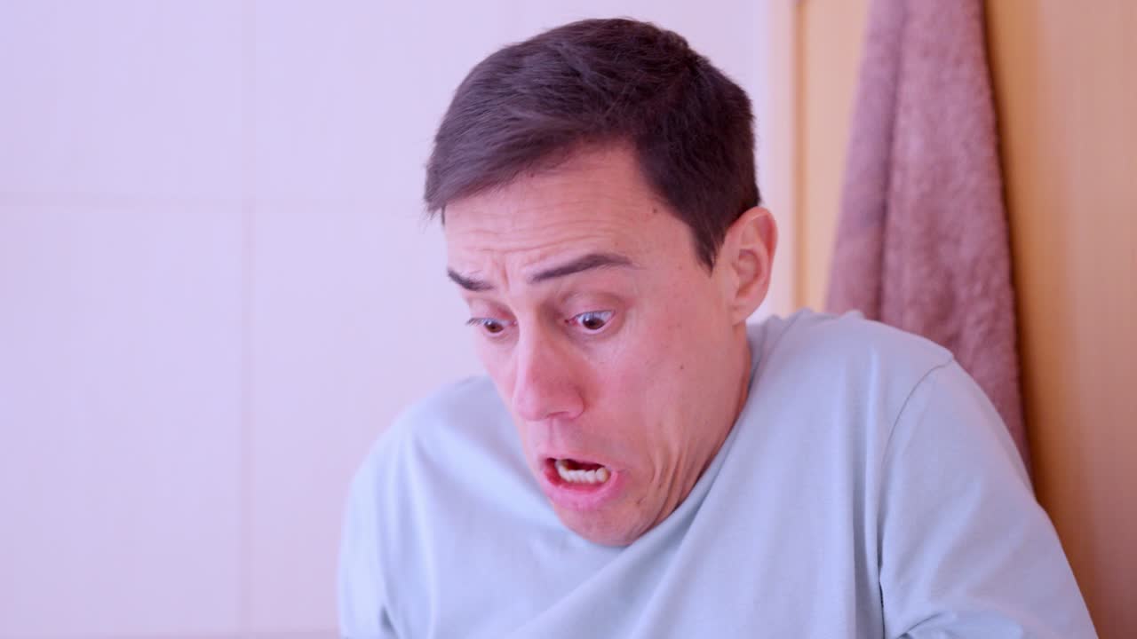 Man blowing nose and looking terrified at handkerchief