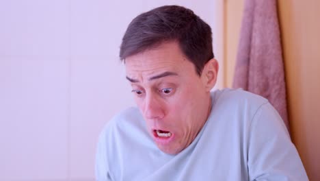 man blowing nose and looking terrified at handkerchief
